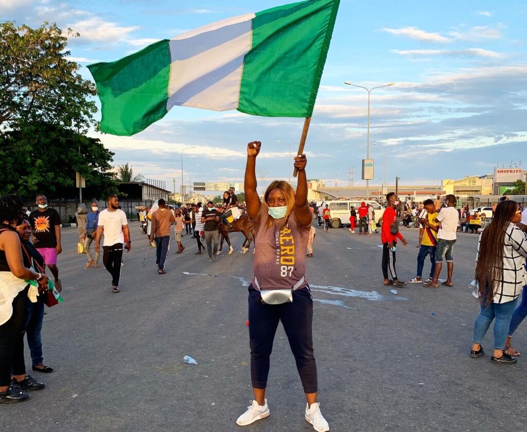 Ogunrinde Medunoye waves a Nigerian flag and raises her fist.
